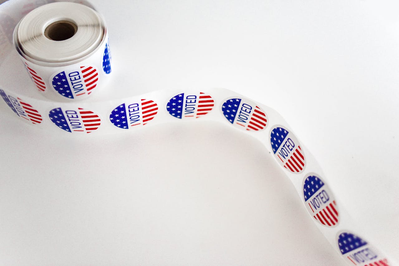 Close-up of a roll of I Voted stickers featuring the American flag design on a white background.